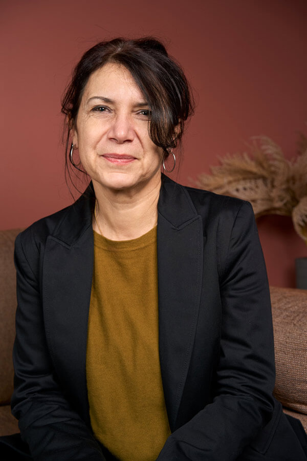 Portrait corporate souriant d'une collaboratrice sur fond terracotta pour un cabinet de conseil & formation à Paris